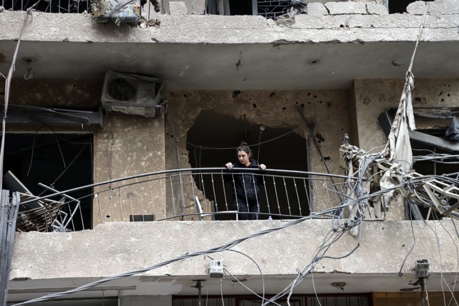 A woman looks over her balcony following Israeli airstrikes on Beirut, Lebanon.