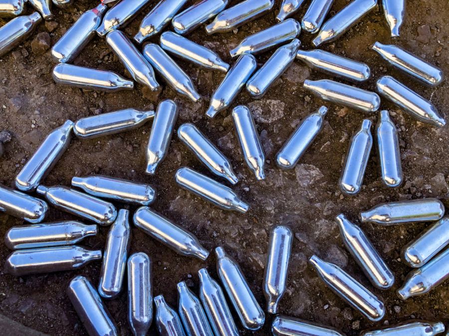 Canisters of nitrous oxide discarded on the ground.