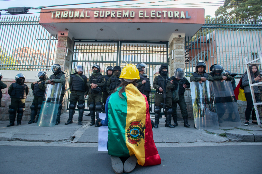 A protester in a Bolivian flag kneels in front of the supreme court in La Paz, Bolivia.